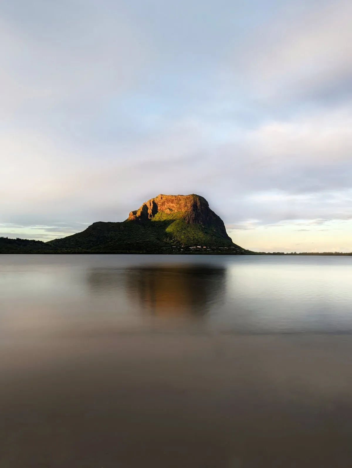 Golden sunrise light illuminating Le Morne mountain in Mauritius with peaceful morning glow