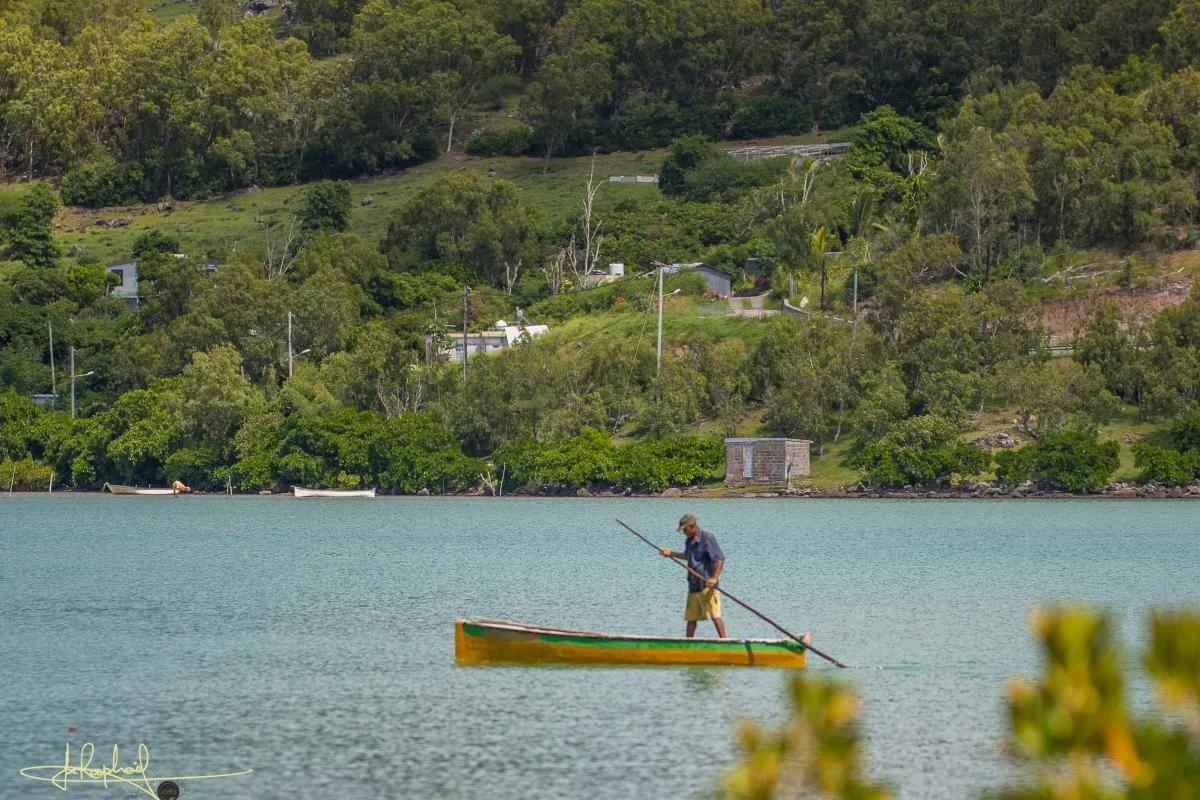 Fisherman sailing a traditional pirogue on calm waters in Rodrigues, Mauritius.