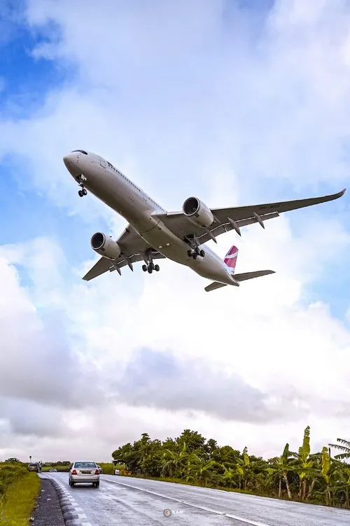 A plane flying over the road at low altitude near airport