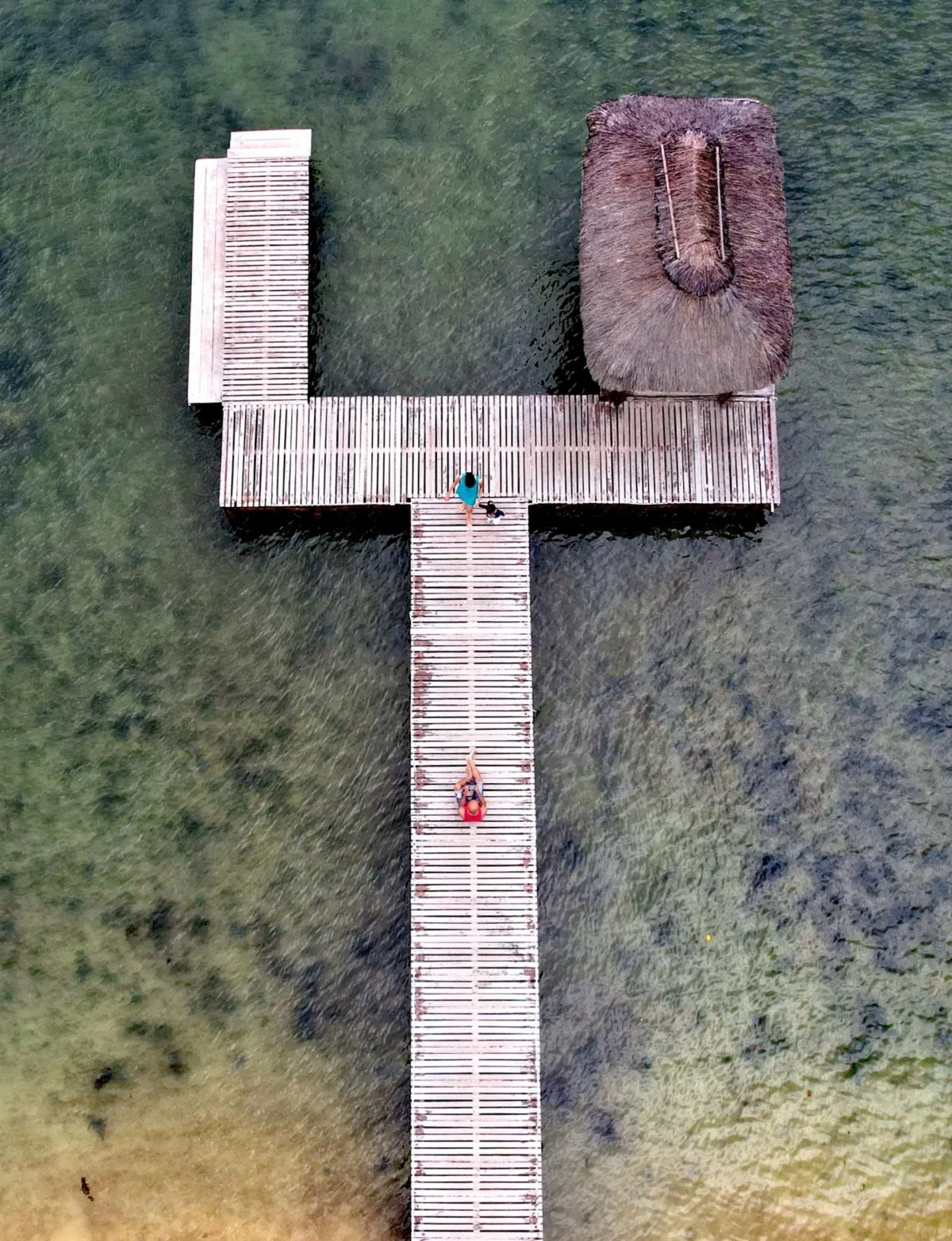 Aerial view of wooden jetty and people walking at Wolmar Beach lagoon in Mauritius