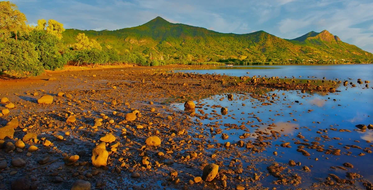 Sunset over the muddy beach of Case Noyale with mountains in the background in Mauritius