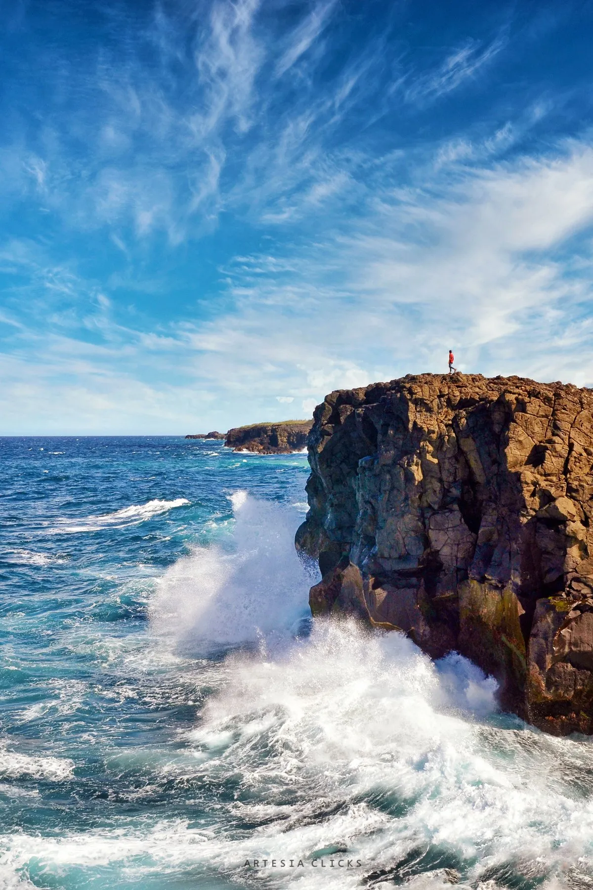 Man contemplating waves crashing on cliffs at Pont Naturel on the wild south coast of Mauritius