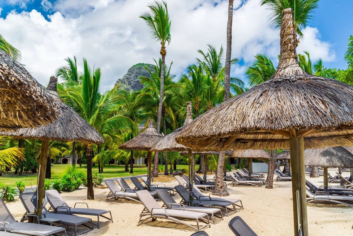 Thatched straw umbrellas and deckchairs on a Mauritius beach near Le Morne