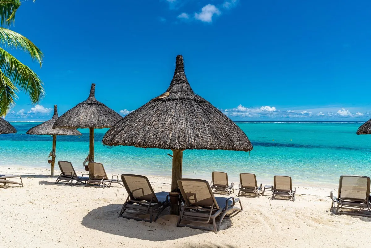 Tropical beach at Le Morne with calm turquoise sea and straw umbrellas in Mauritius