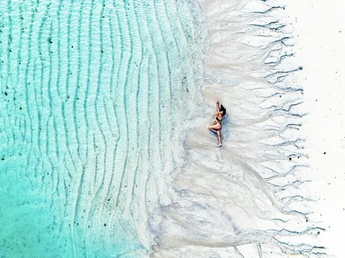 Aerial view of girl & natural patterns on beach