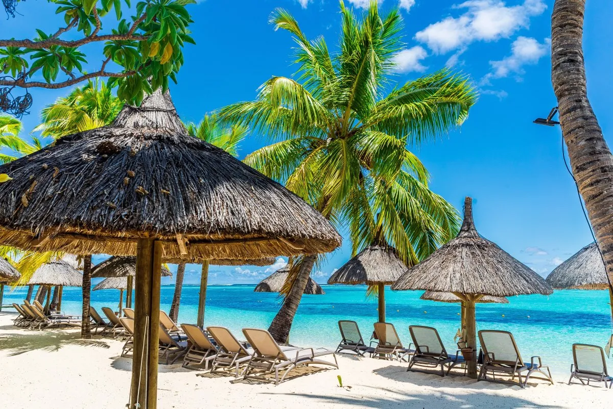 Turquoise ocean and thatched umbrella at Le Paradis Beachcomber resort in Mauritius