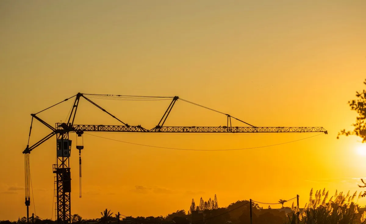 Silhouette of a tower crane at sunset in Mauritius against an orange sky