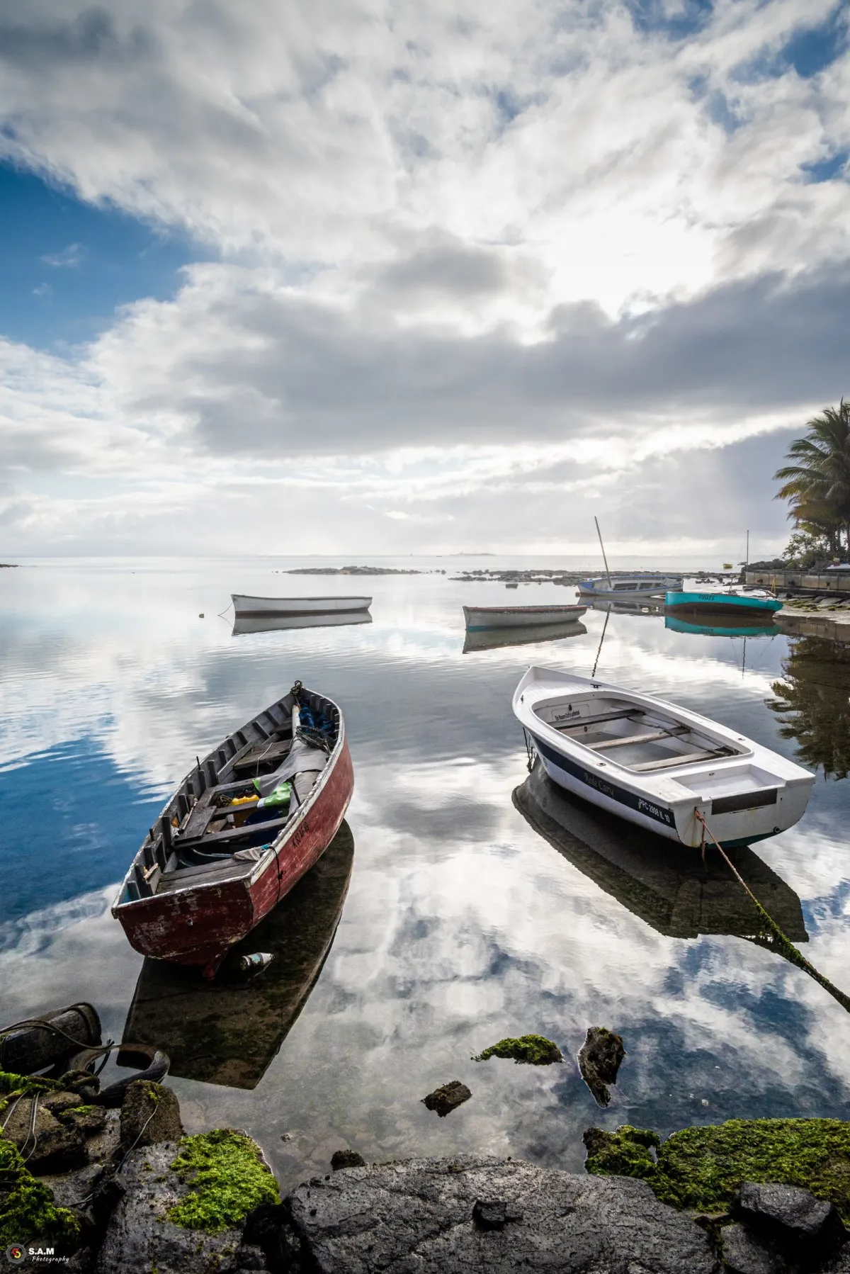 Calm reflection of sky and pirogues at Mahebourg bay in Mauritius on a quiet morning