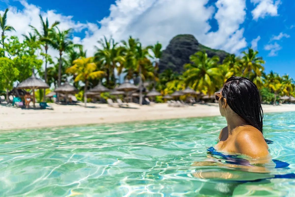 Girl swimming in clear lagoon water near Le Paradis Hotel and Le Morne mountain in Mauritius