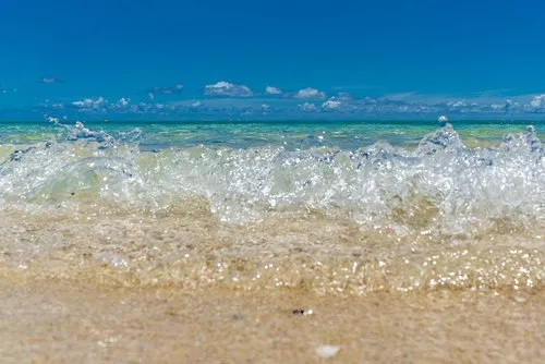 Lagoon sparkling waves close up hitting beach
