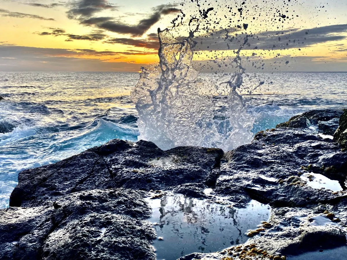 Waves splashing against volcanic rocky shore at Albion in Mauritius with a sunset backdrop