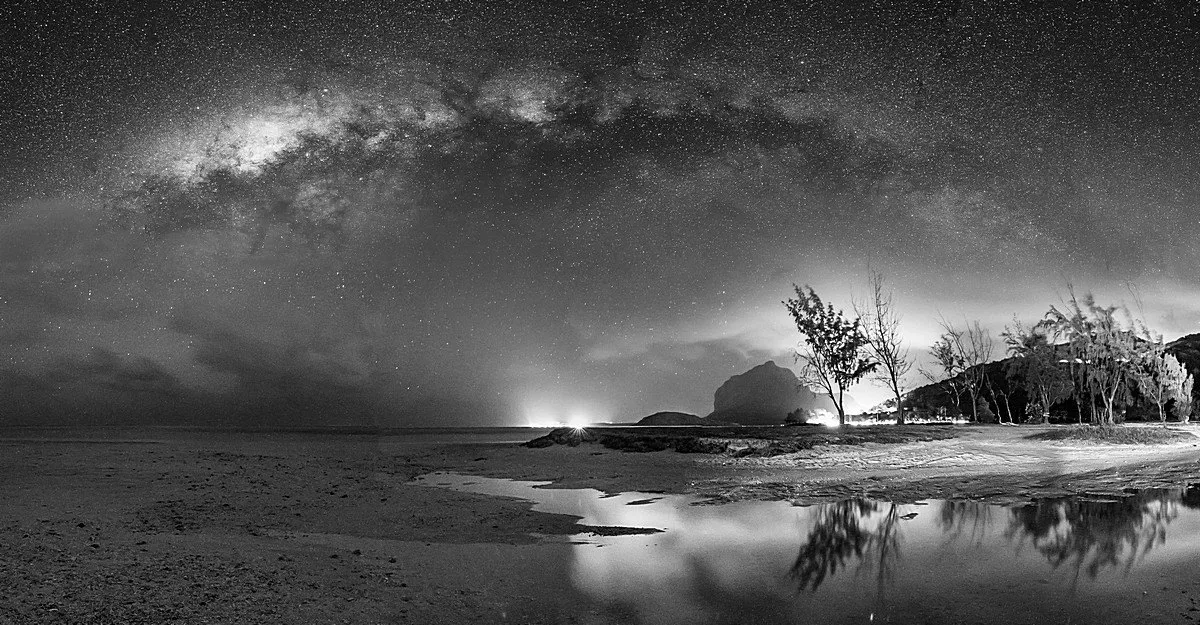 Black and white Milky Way panorama over La Prairie beach in Mauritius with night sky and beach landscape.