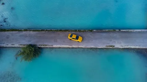 Odd scene of yellow car surrounded by the sea