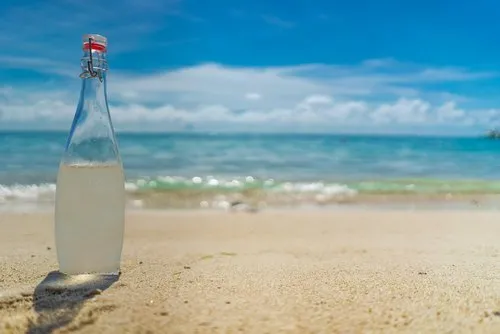 Chilled glass water bottle laid on hotel beach