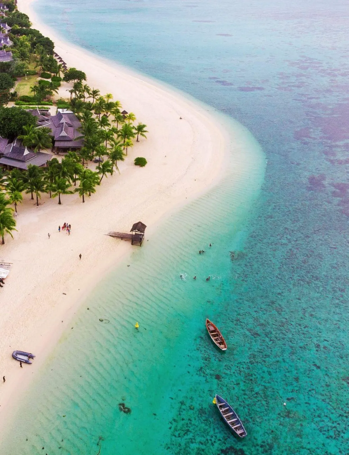 Aerial view of Le Morne Beach with turquoise lagoon and traditional boats in Mauritius