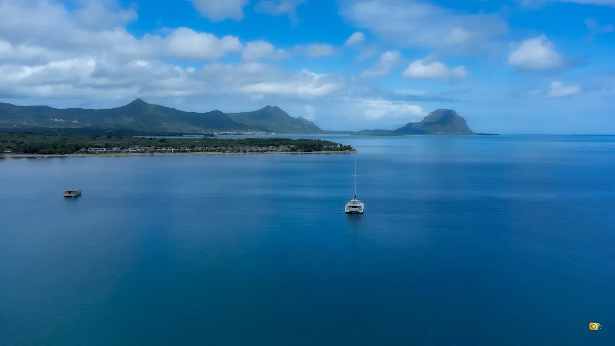 Drone shot of Le Morne mountain and beach in Mauritius with clouds and a boat