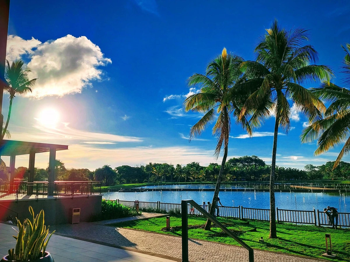 Lake at Mahogany Beau Plan in Mauritius with palm trees, blue sky, and bright tropical sunlight.