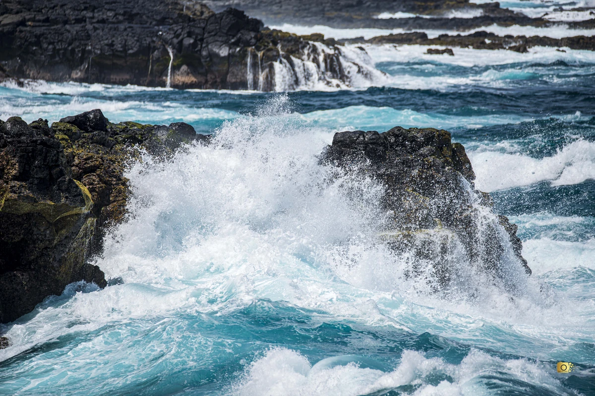 Powerful waves crashing against dark volcanic rocks at Pont Naturel, south of Le Bouchon village on the south-east coast of Mauritius.