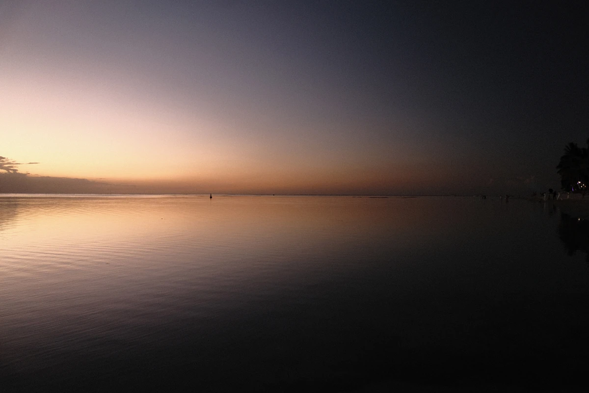Artistic sunset reflection on calm water at Flic en Flac, with soft evening colours and a peaceful lagoon scene.