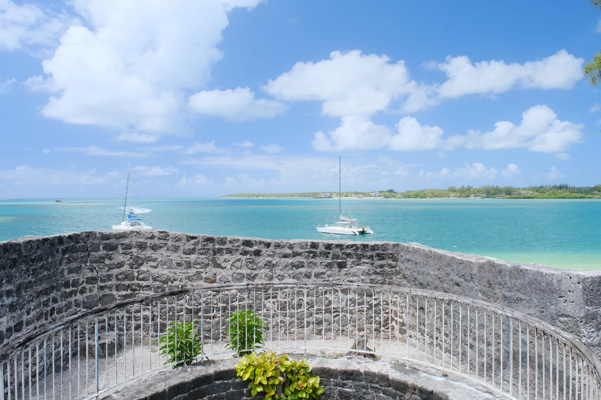 View of Trou d’Eau Douce lagoon from the old lime kiln, with stone walls, turquoise water, sailboats and the east coast of Mauritius.