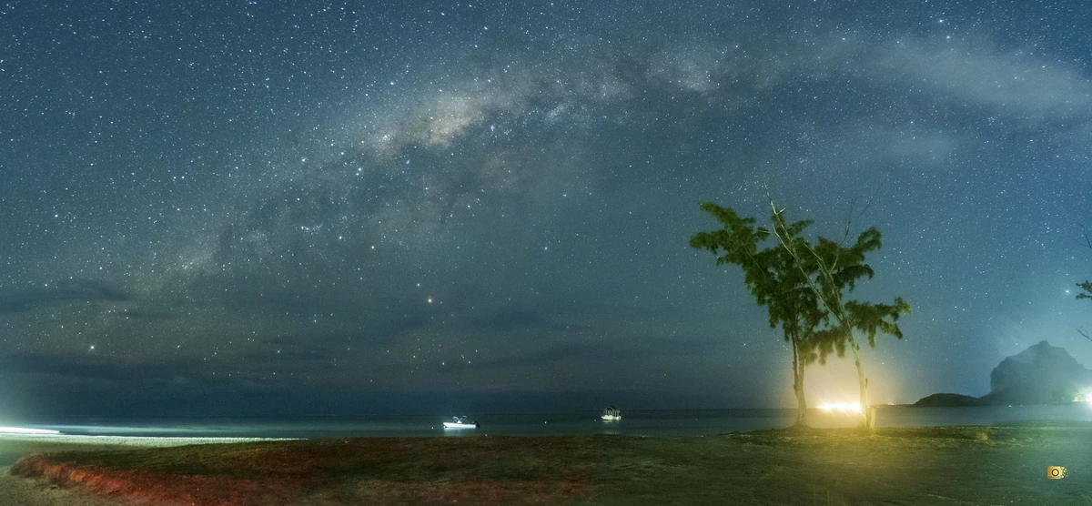 Milky Way above La Prairie beach with Le Morne mountain silhouette in the background at night.