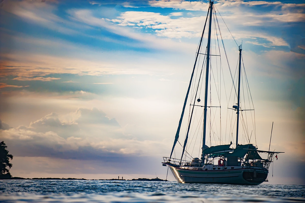 Anchored sailboat off La Cuvette Beach in Grand Baie during golden hour under a dramatic cloudy sky in Mauritius.