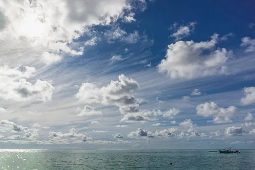 Windy clouds above ocean and fishing boat
