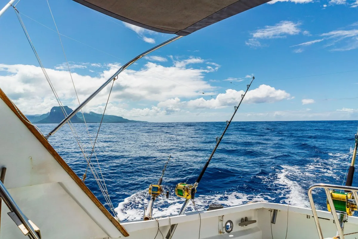 White fishing boat with golden reels on the deep blue sea of Mauritius under a clear sky