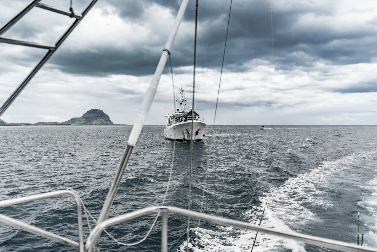 Mauritius Coast Guard naval ship navigating rough grey seas near Le Morne under cloudy sky