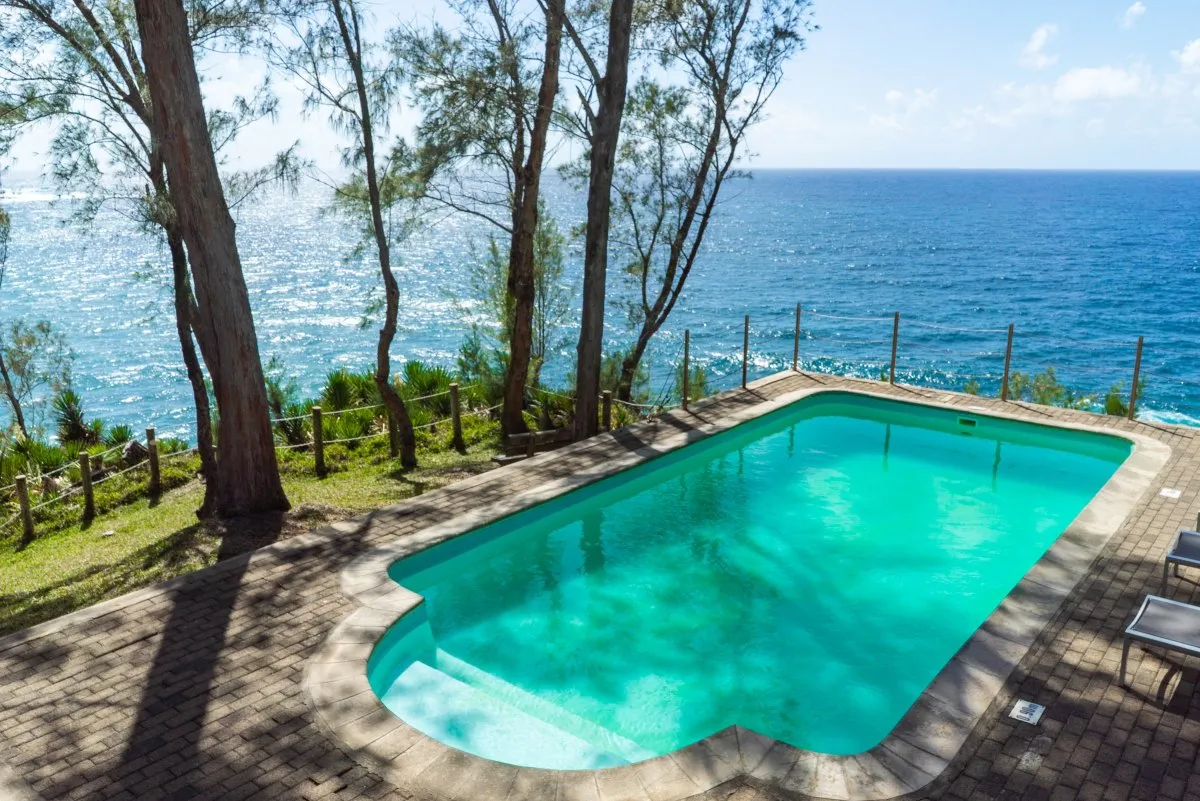 Swimming pool at Andrea Lodge next to cliffs and open sea in Mauritius surrounded by nature