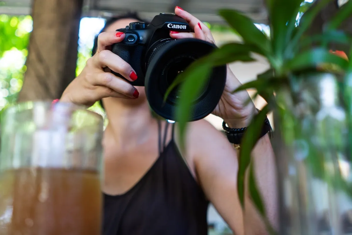 Young woman in black dress holding and reviewing photos on Canon camera in Mauritius