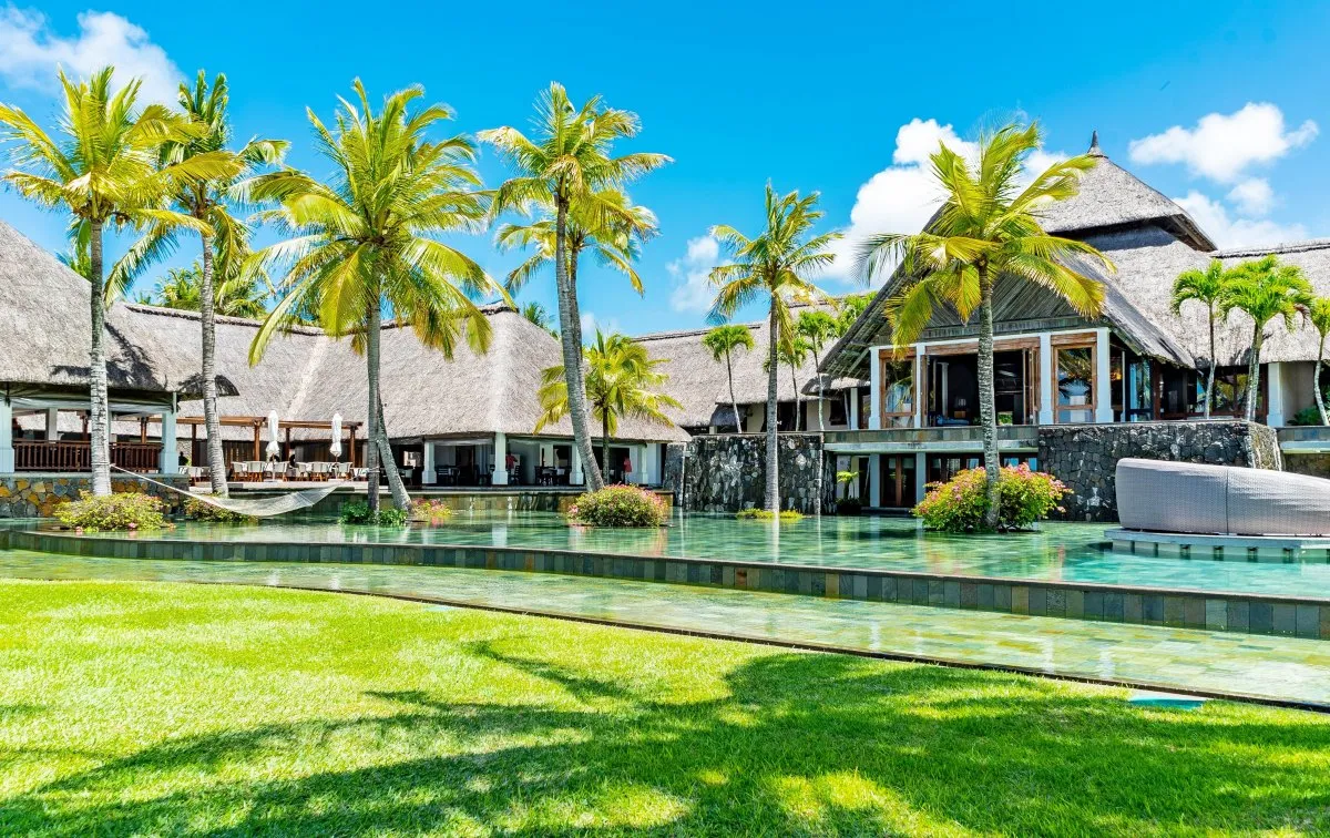 Front view of Constance Belle-Mare Plage hotel with infinity pool and coconut trees in Mauritius