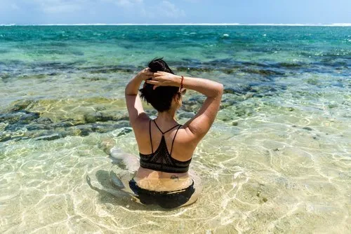 Woman sitting in black swimsuit in shallow sea