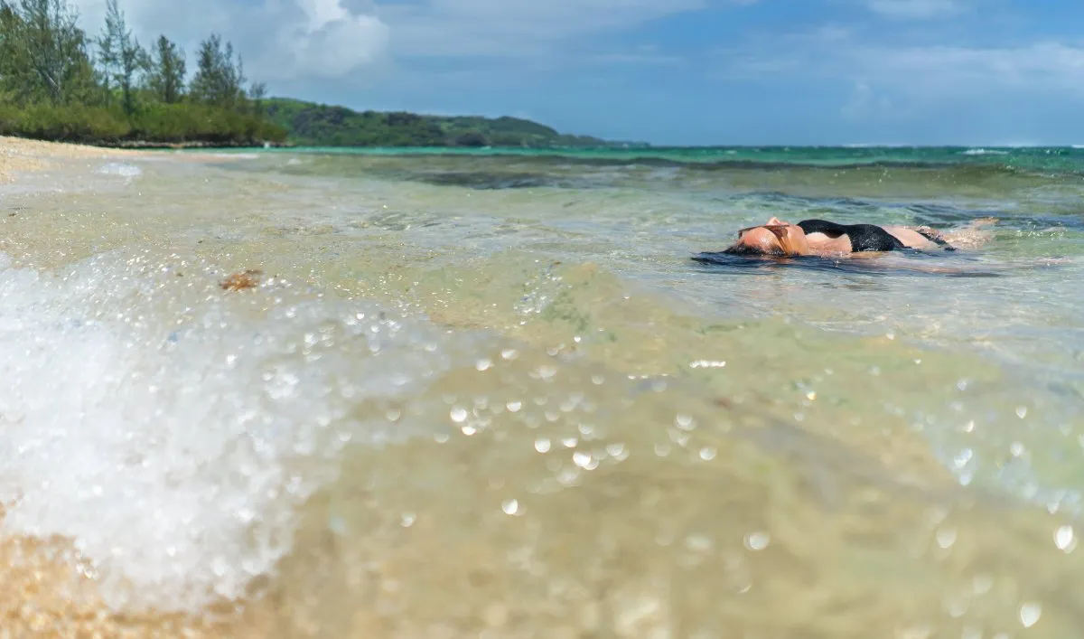 Woman floating peacefully on clear, calm water at a secluded beach in Mauritius