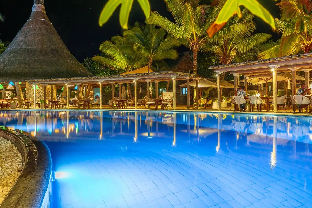 Romantic beachside restaurant with illuminated pool and dimmed lights at night in Mauritius