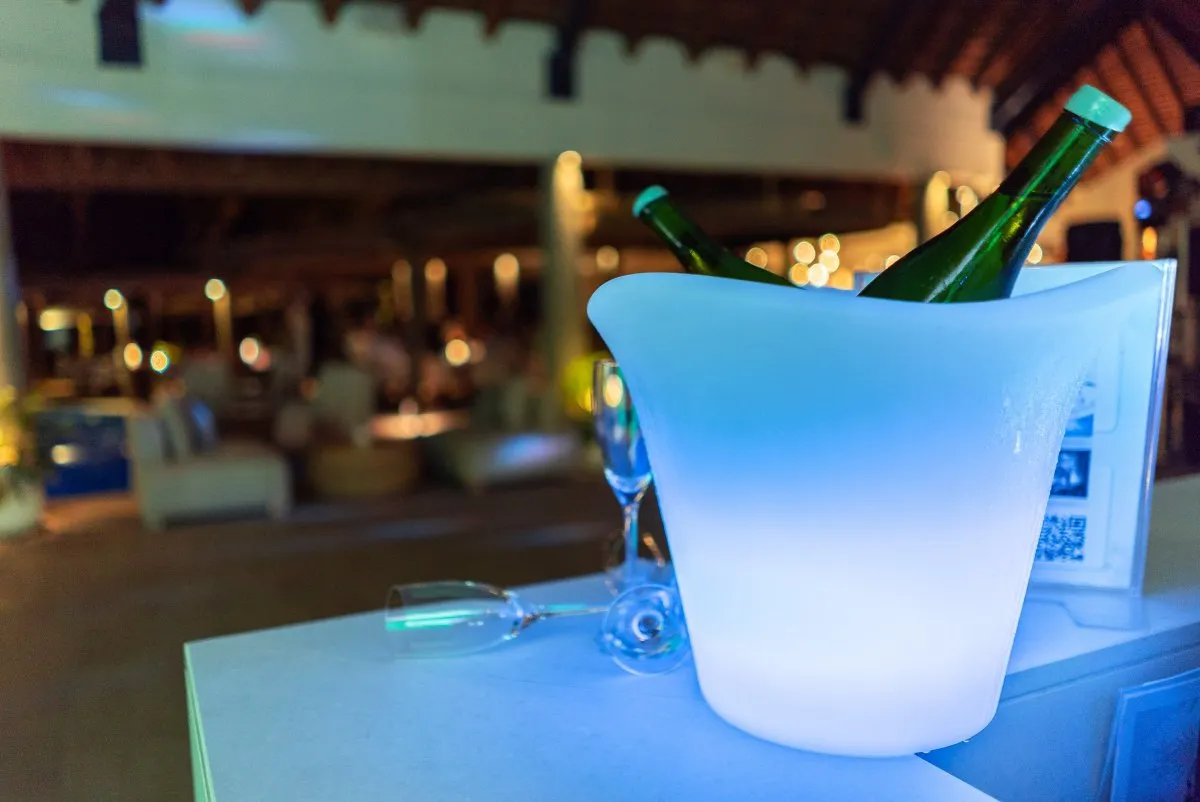 Ice box bucket with chilled water bottles and flutes at a restaurant in Mauritius.