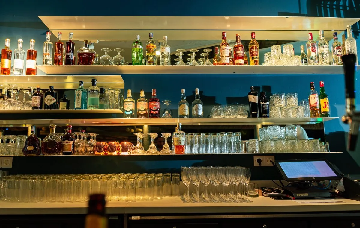 Top liquor bottles displayed at a bar in Mauritius with glasses and POS equipment