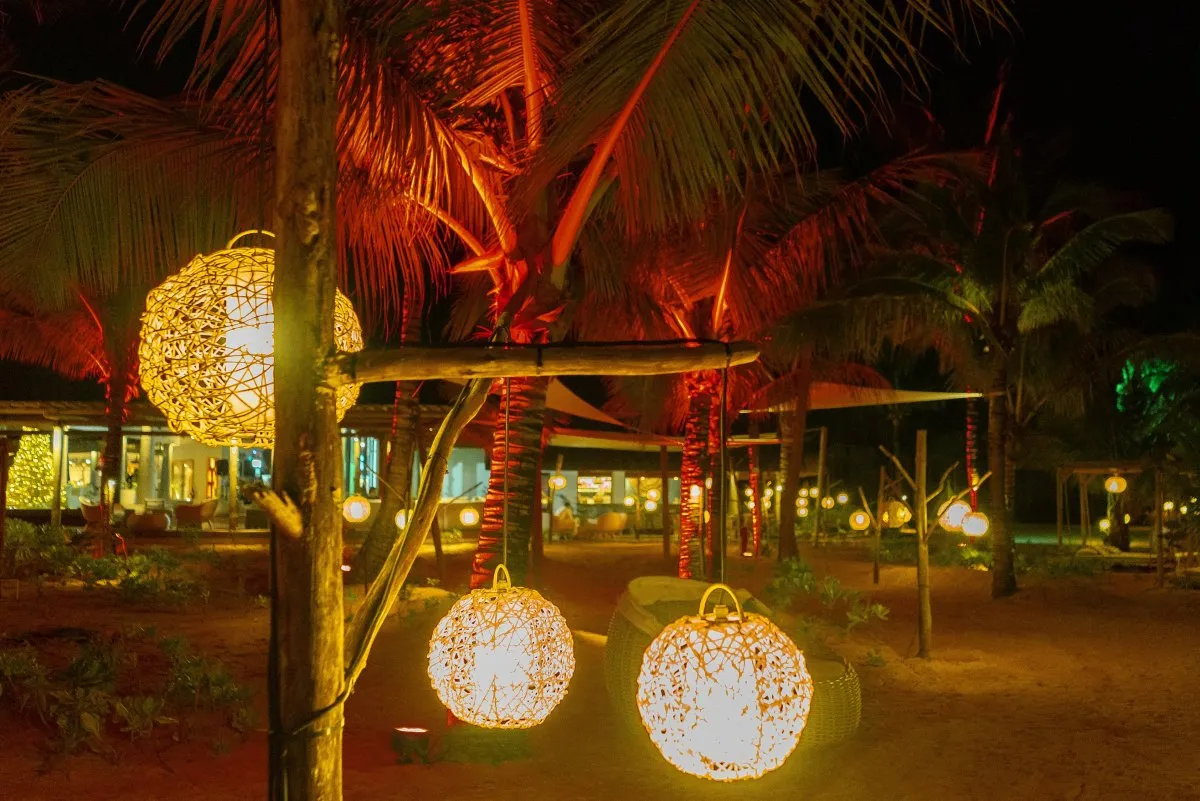 Illuminated outdoor round lanterns hanging on wooden poles at C Beach Club beach in Mauritius