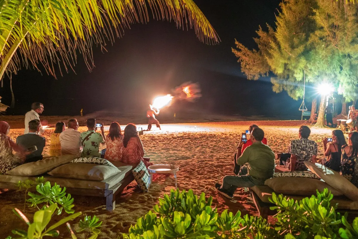 Performer breathing fire during a fire eater show on a beach in Mauritius with an engaged crowd watching