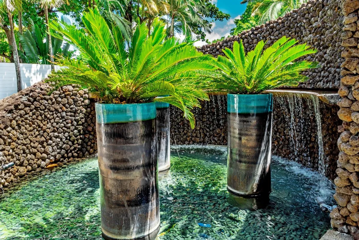 Sago palm trees in high black metal pots surrounded by a fountain at Constance Belle-Mare Plage Hotel, Mauritius