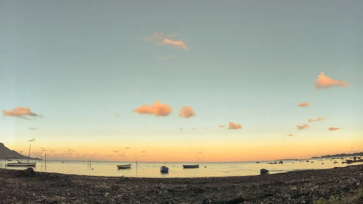 Vintage-style dramatic sunset sky over Rivière Des Creoles beach with a boat in Mauritius