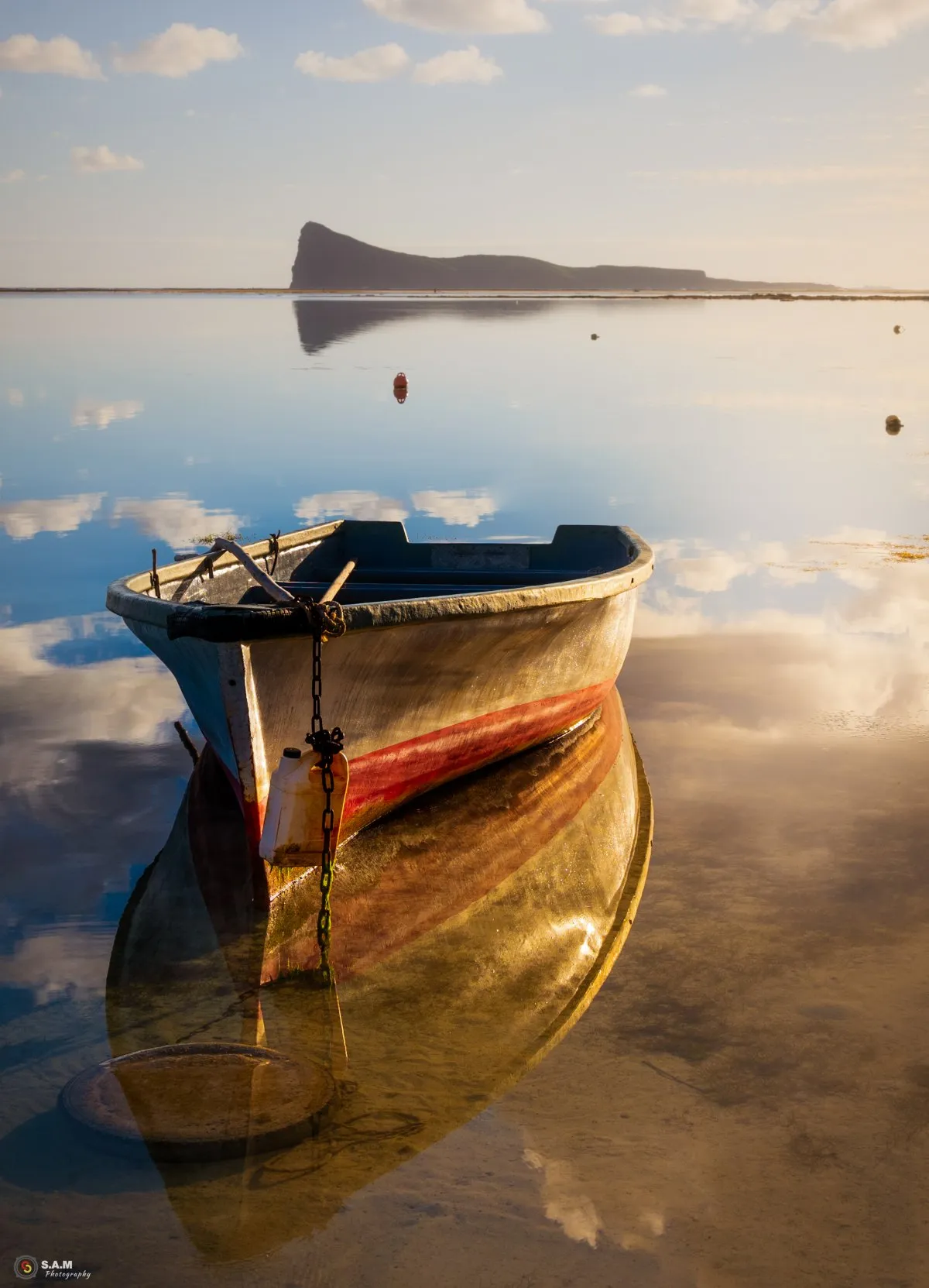 Moored fisherman boat reflecting in shallow lagoon waters near Coin de Mire island in Mauritius