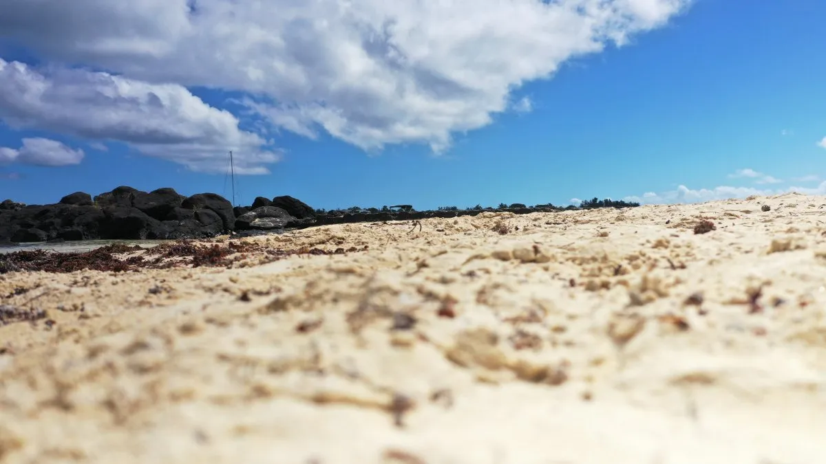 Blurred close-up image of sand on a Mauritius beach with blue sky background