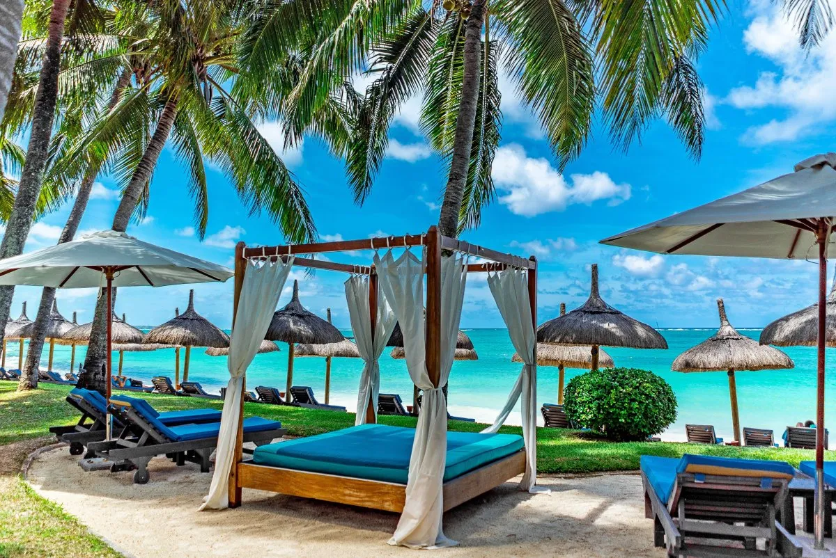Wooden canopy beach bed shaded at Constance Belle-Mare beach with turquoise ocean in Mauritius