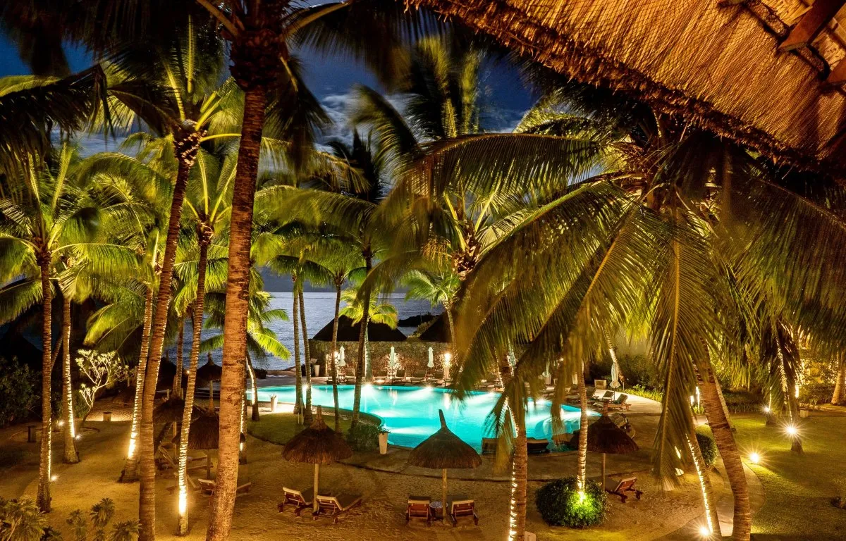 Nighttime pool behind coconut trees with moon reflection at Constance Belle-Mare Plage in Mauritius