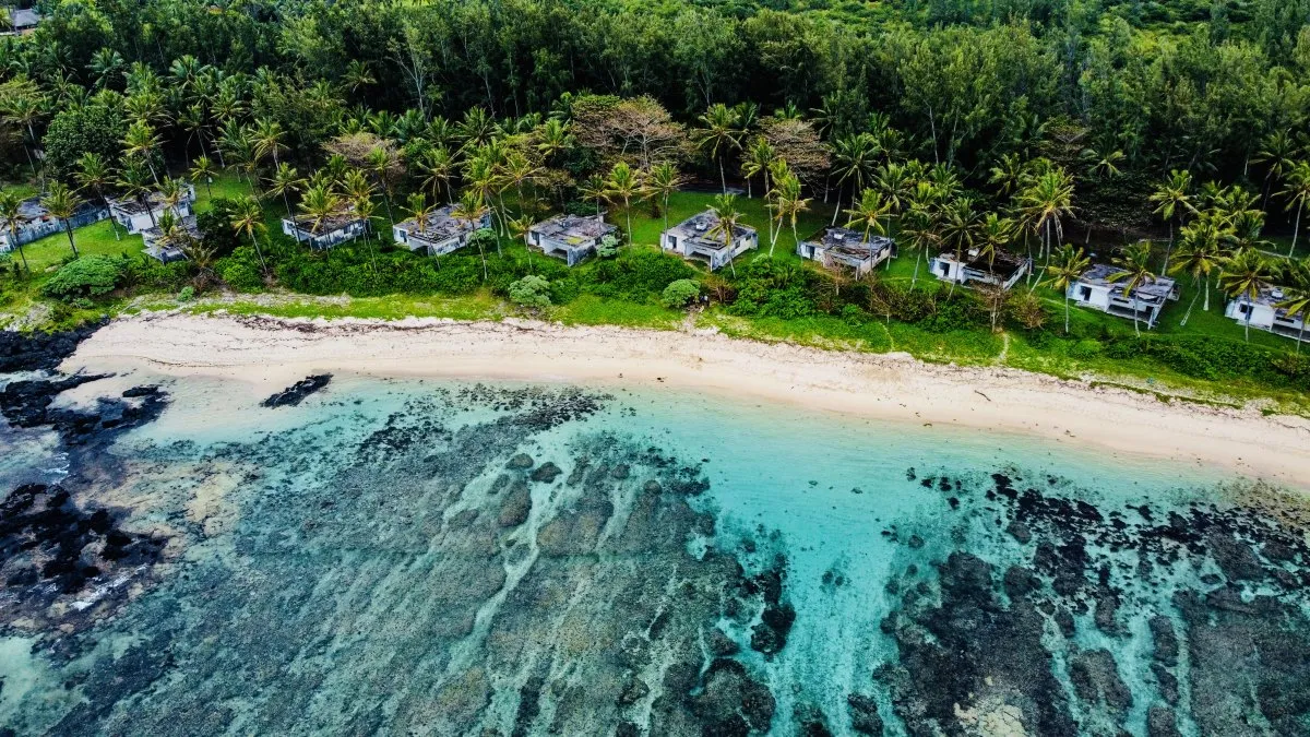 Aerial view of rocky turquoise lagoon, villas, and wild beach in southern Mauritius