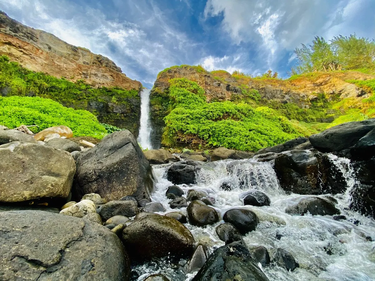 Waterfall cascading down cliffs surrounded by plants and rocks in Souillac, Mauritius