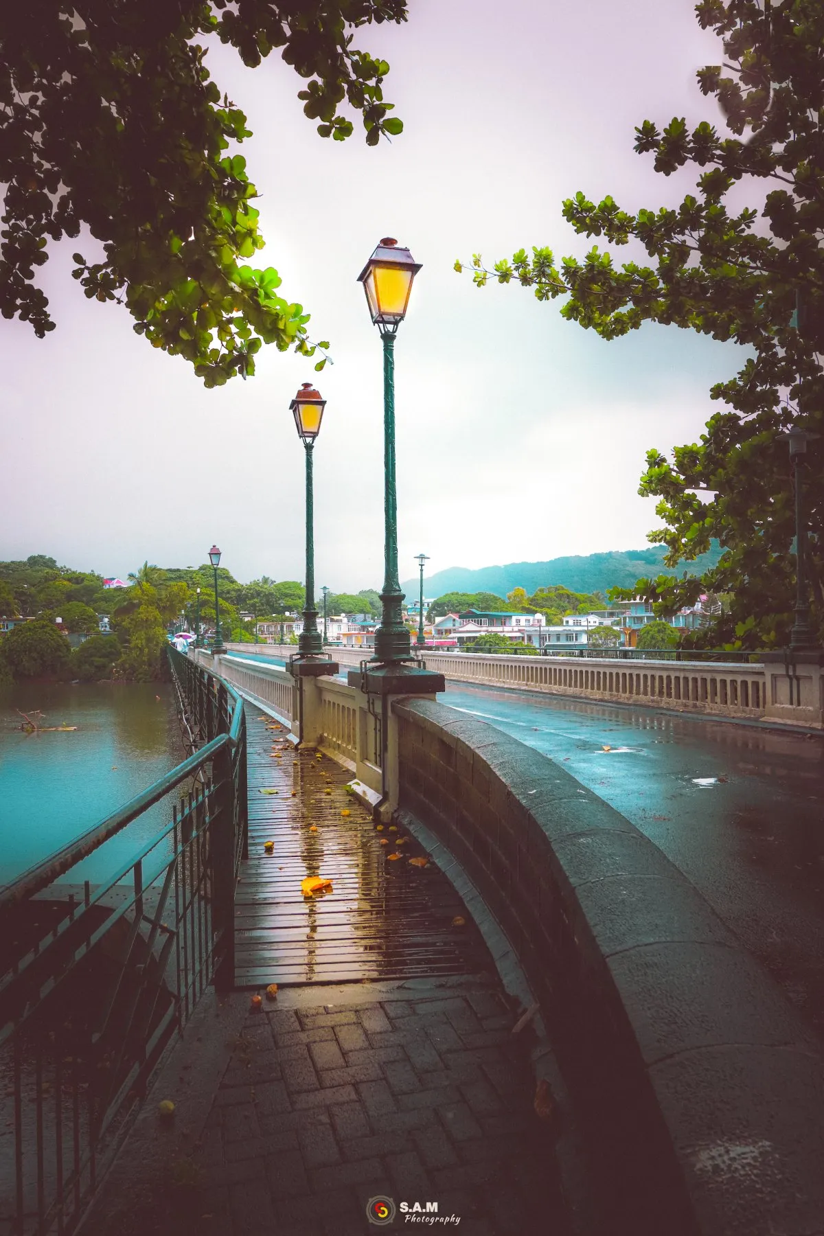 Cavendish Bridge in Mauritius linking Mahebourg to Ville-Noire with street lights reflecting on a wooden pathway in gloomy weather