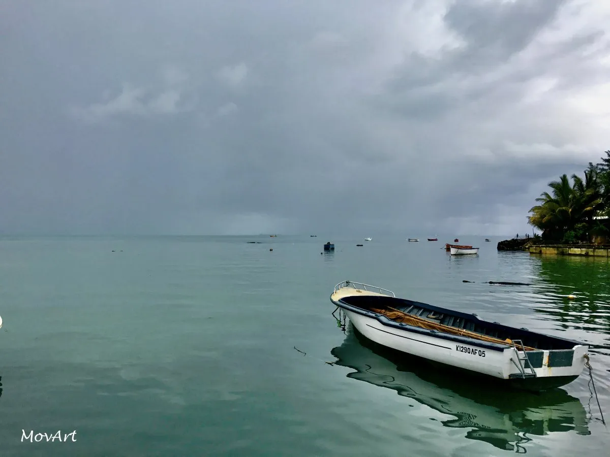 Foggy morning over calm lagoon with fisherman boat at Mahebourg Waterfront in Mauritius