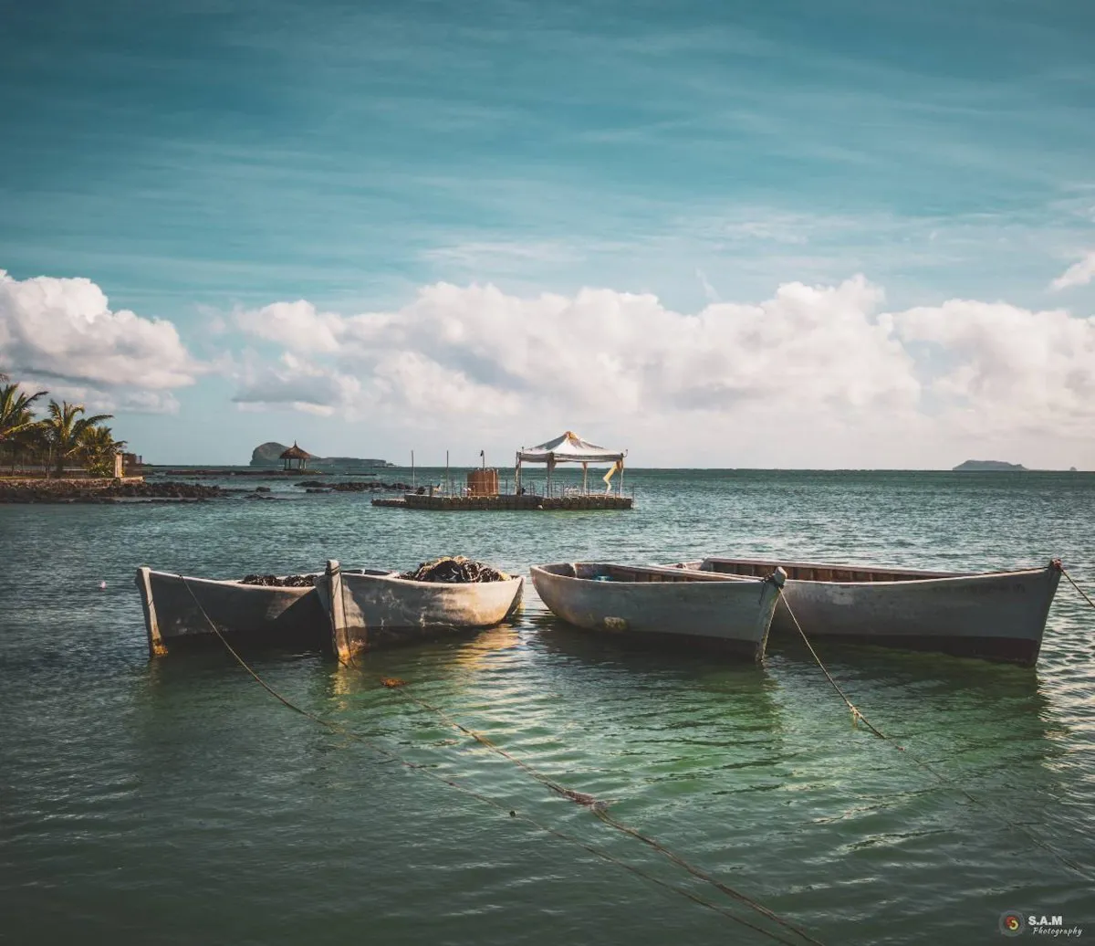 Four white fishing boats lined up in the calm lagoon of Grand Gaube, Mauritius near the beach
